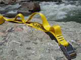 yellow polyester tie down cam strap with a sewn handle on a rock by whitewater rapids